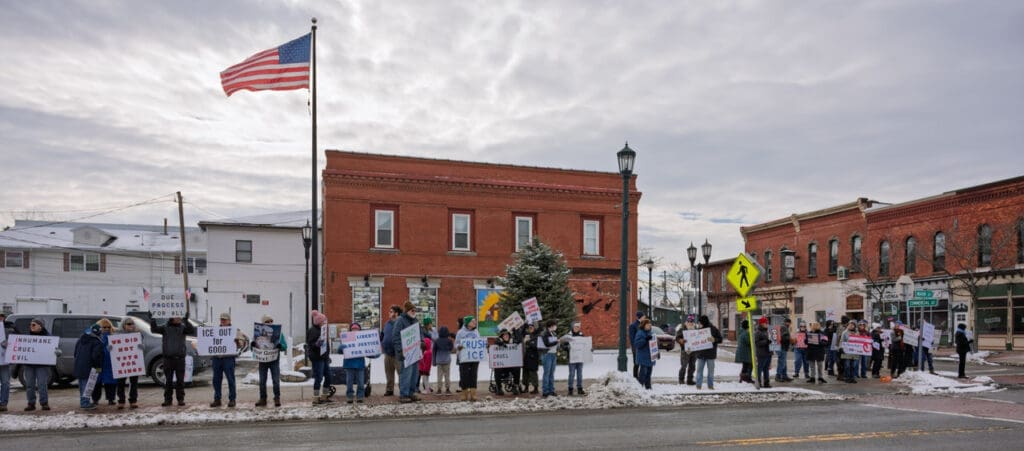 People holding protest signs in snowy town street.