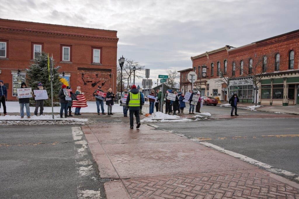 Group protesting with signs on snowy city street corner.