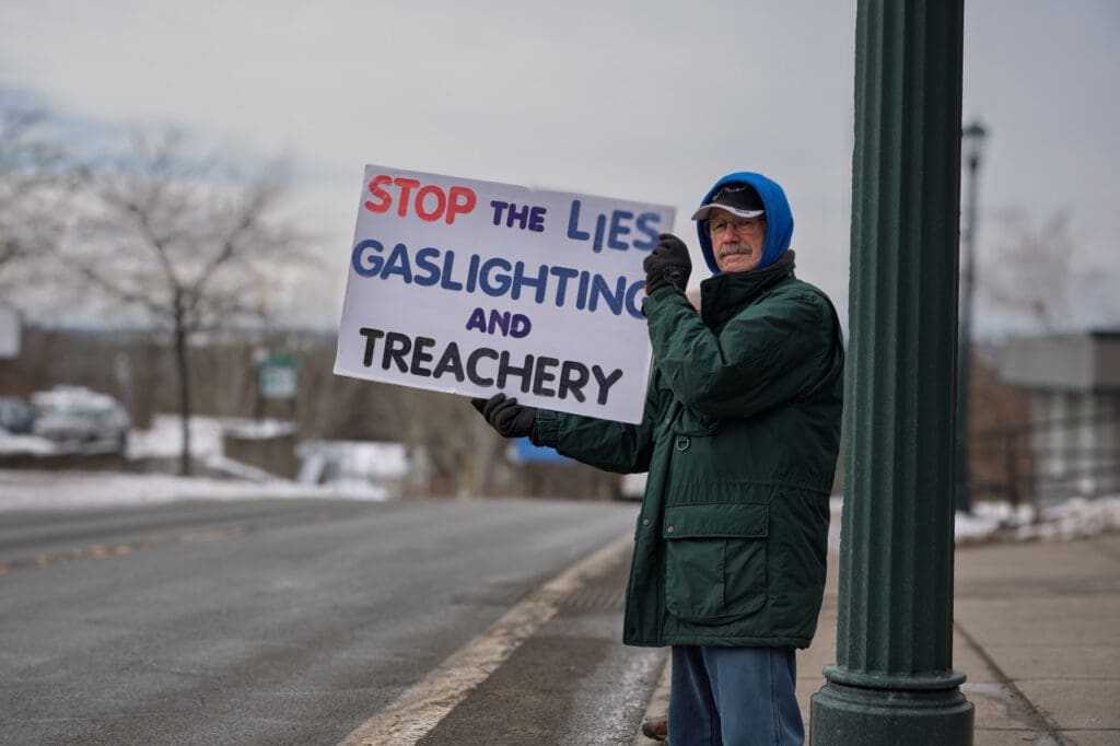 Protester with sign against lies and gaslighting.