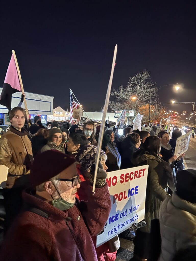 Night protest with people holding signs and flags.