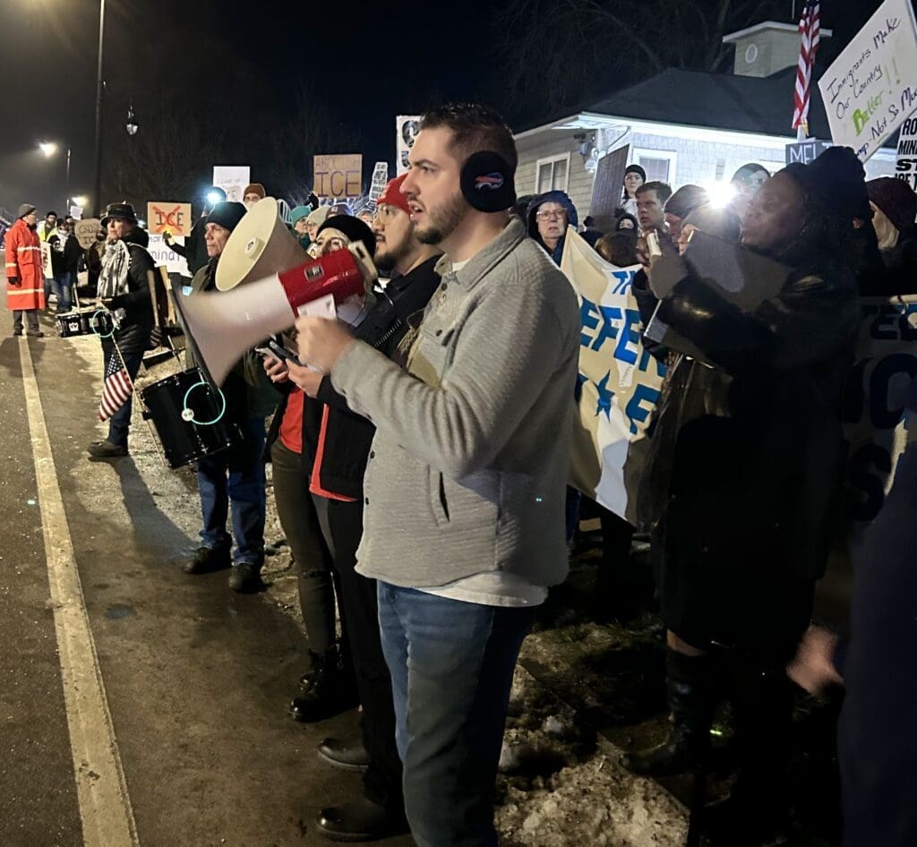 People protesting with megaphone and banners at night.