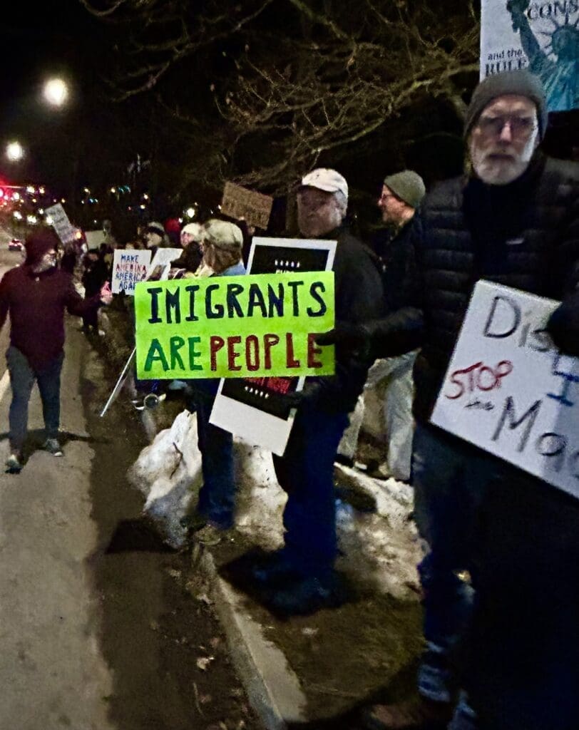 Protesters holding signs at night on the street.