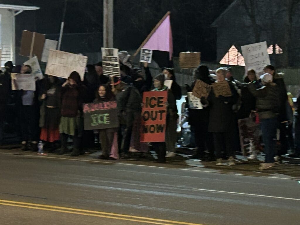 Crowd holding protest signs at night.
