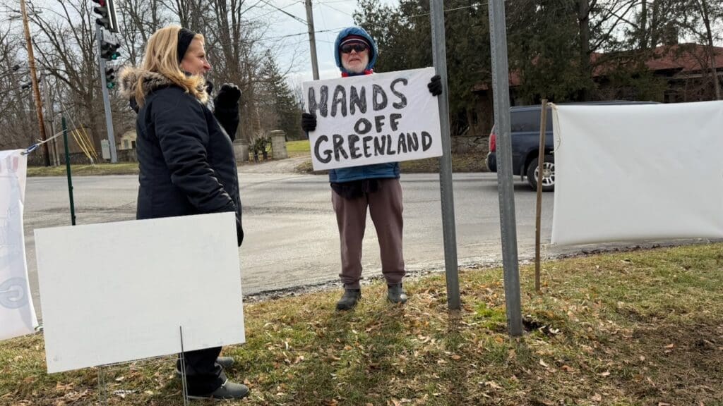 People protesting with 'Hands Off Greenland' sign.