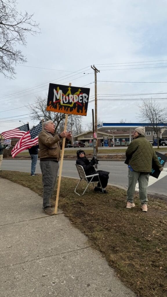People protesting with signs and American flags.