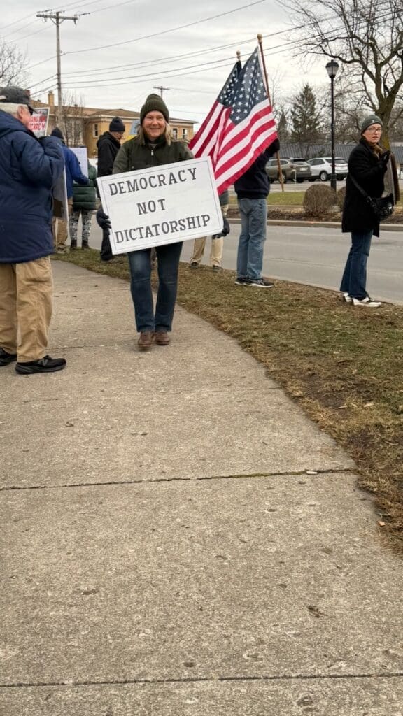 Protester holds 'Democracy not Dictatorship' sign at rally.