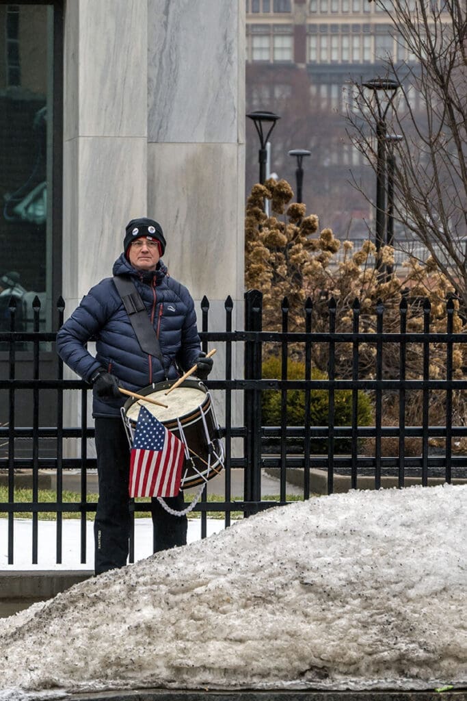 Drummer with American flag on a snowy street.