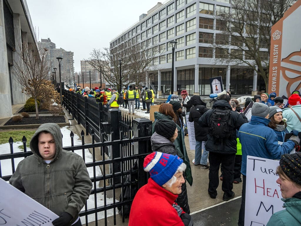 Protesters gather with signs outside urban building.