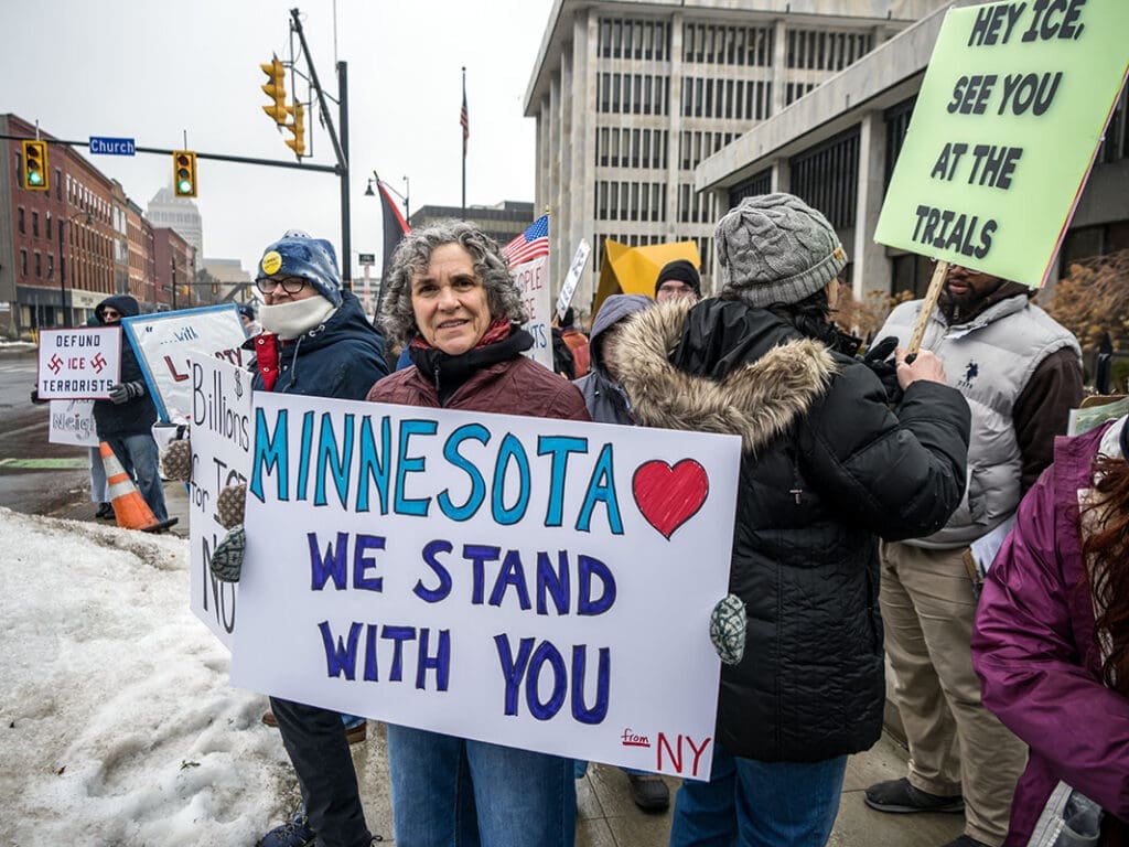 Protesters in winter clothing holding various signs.