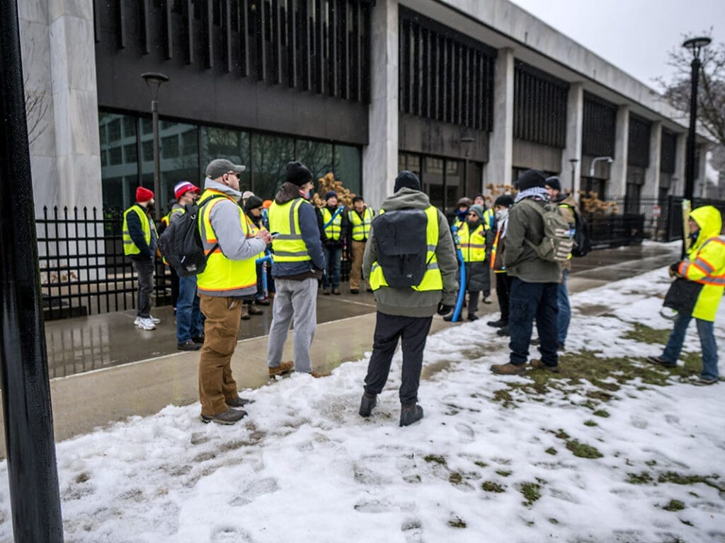 Group in reflective vests outside building in winter.