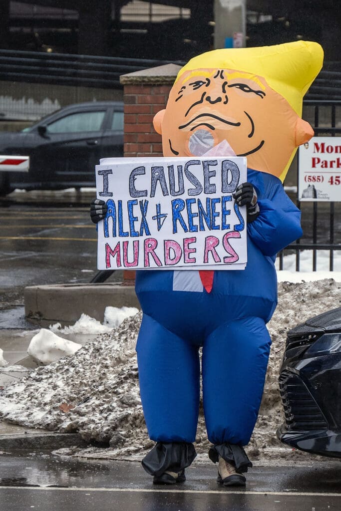 Person in costume holding protest sign on street.