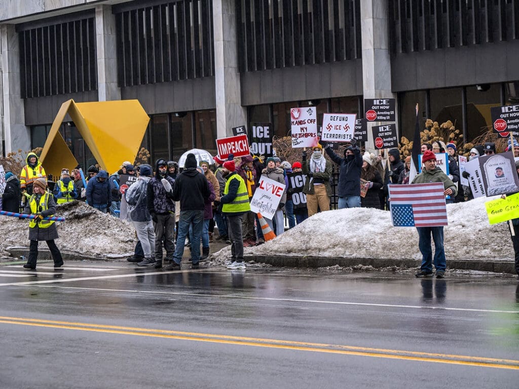 Protesters holding signs outside a large building.