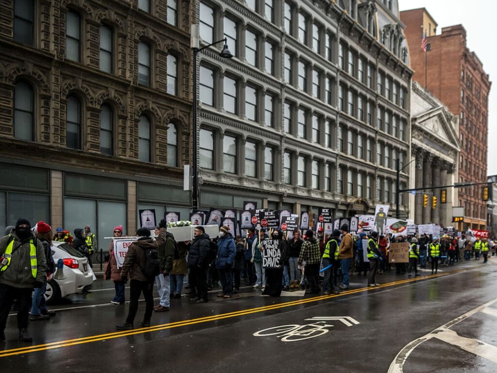 Protesters march on city street with signs.