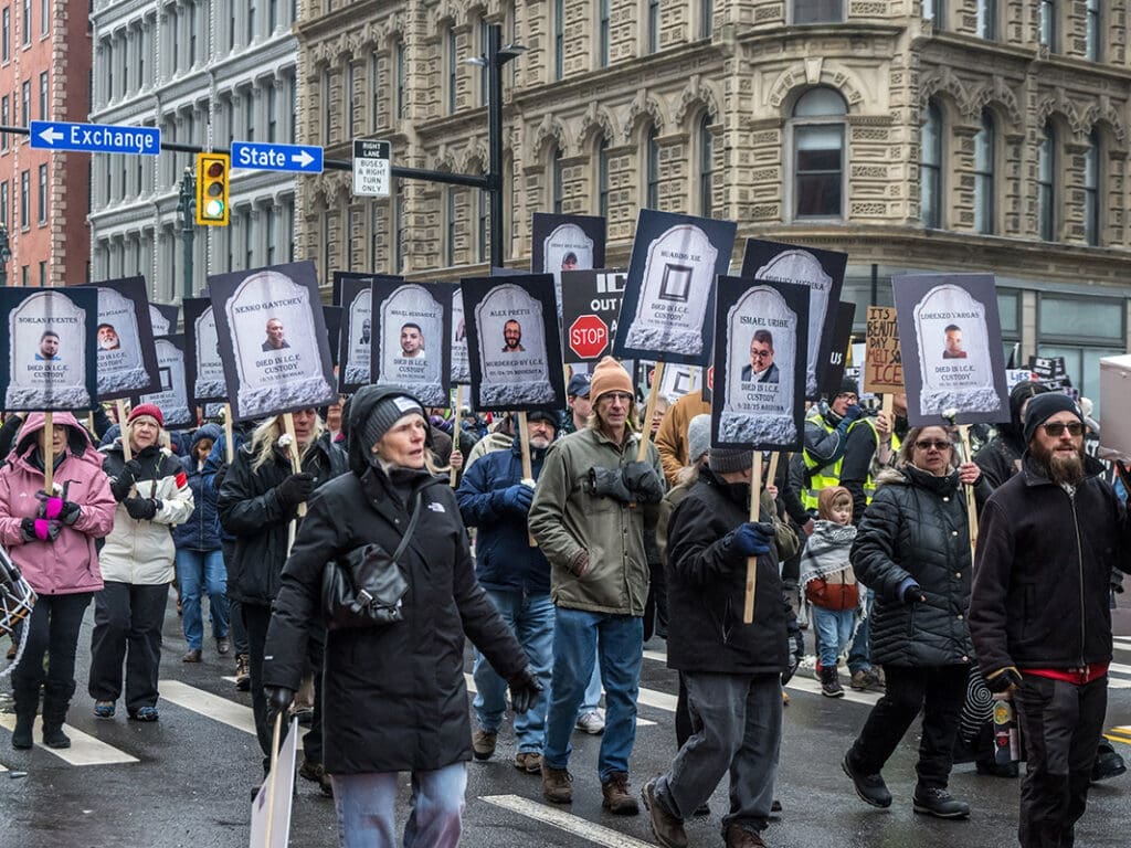 Protesters holding signs with faces and names.