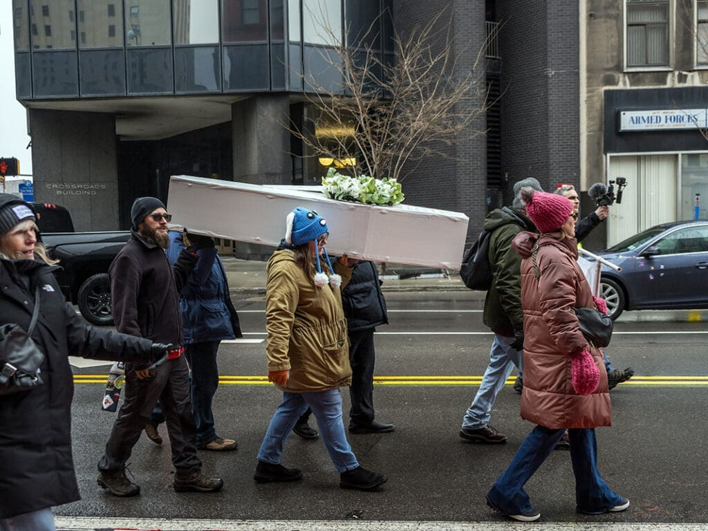 People marching with a coffin in a city protest.