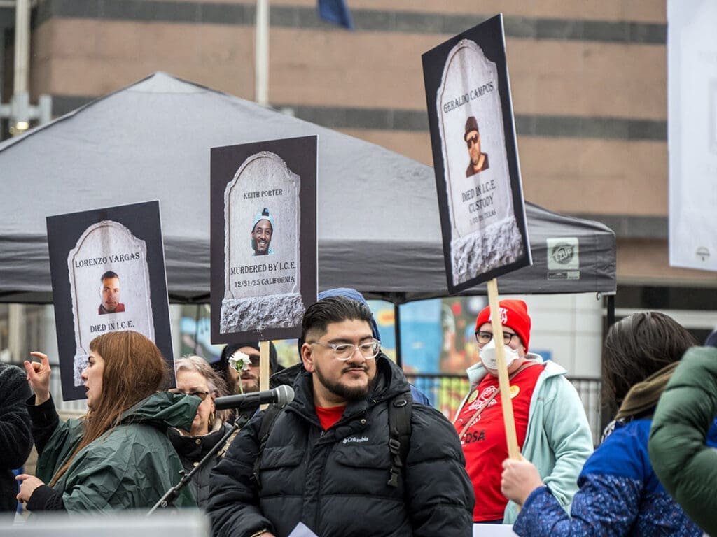 Protesters display signs with images, condemn ICE policies.