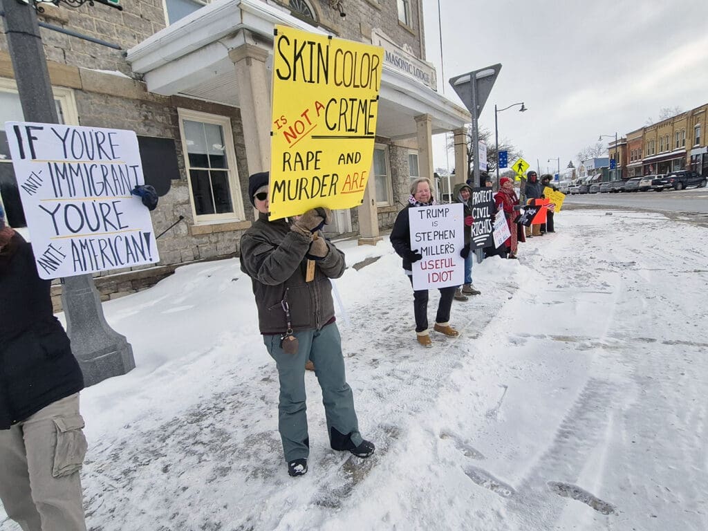 Protest on snowy street with various signs.