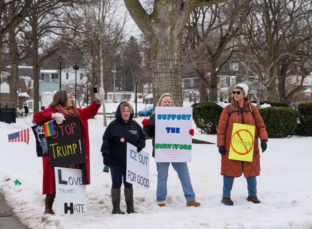 Protesters holding signs in snowy park.