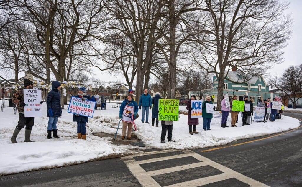 Protesters with signs on a snowy street corner.