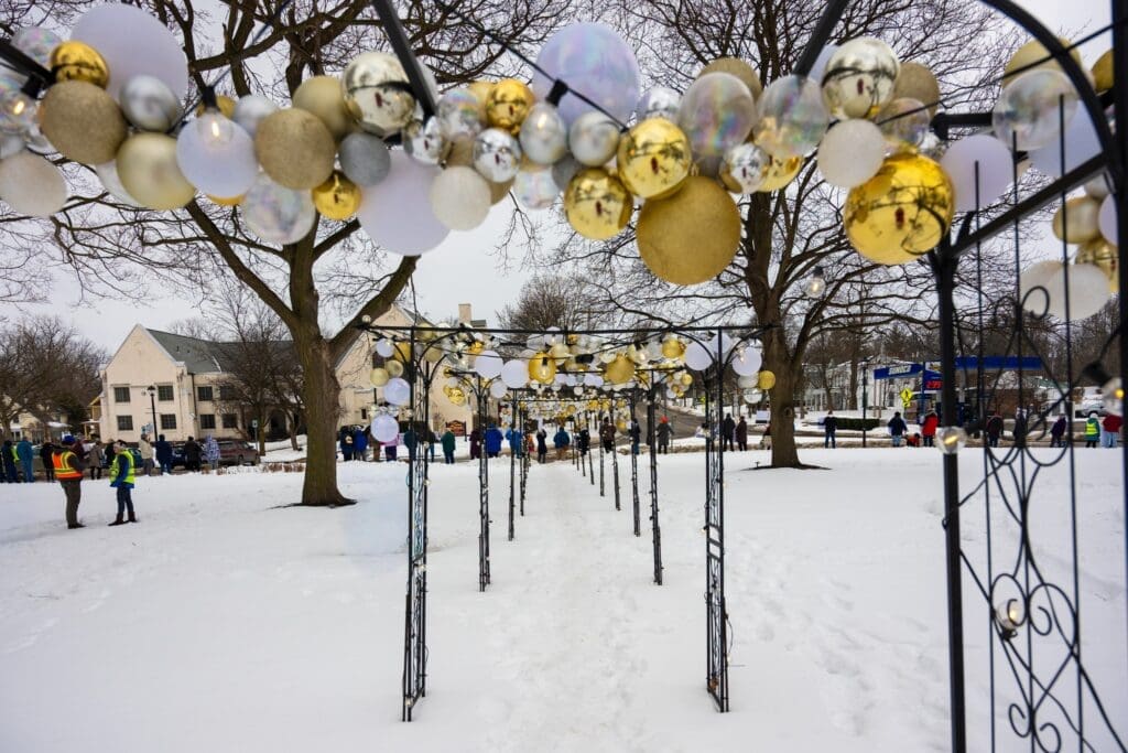 Snowy park with decorative archways and crowd gathering.