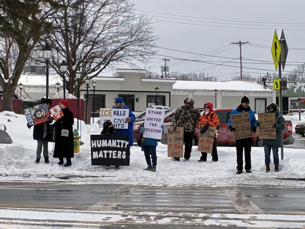 Protesters holding signs in snowy urban area.