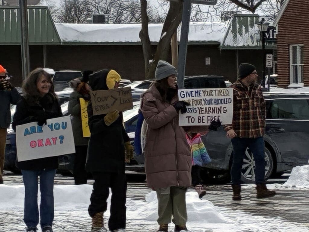People holding protest signs in snowy street.