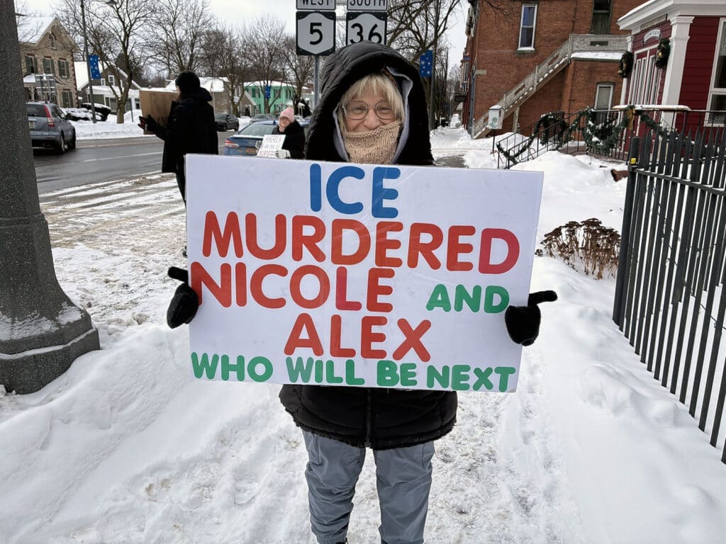 Protester holding sign in snowy street demonstration.