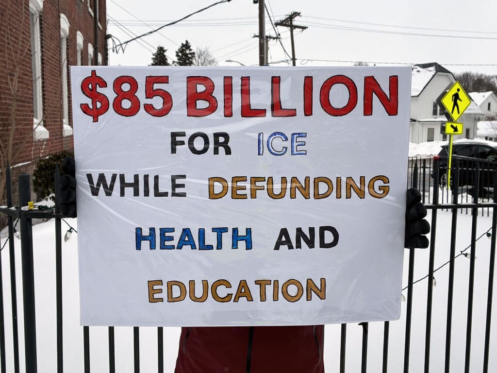 Protest sign about funding ICE over education, health.