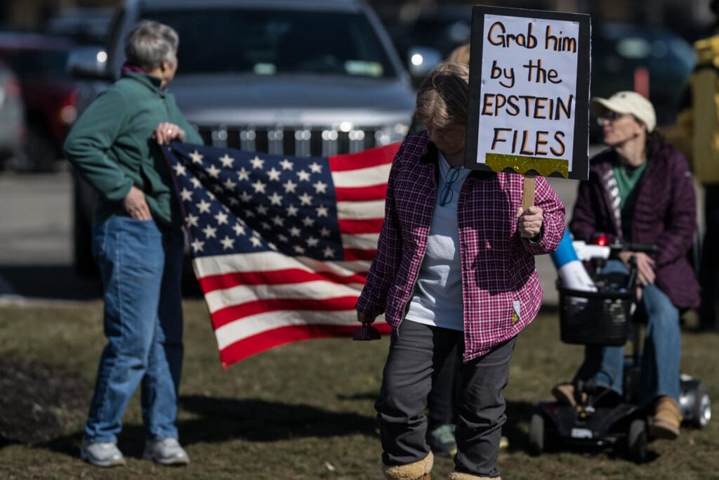 Protesters holding Epstein files sign with American flag