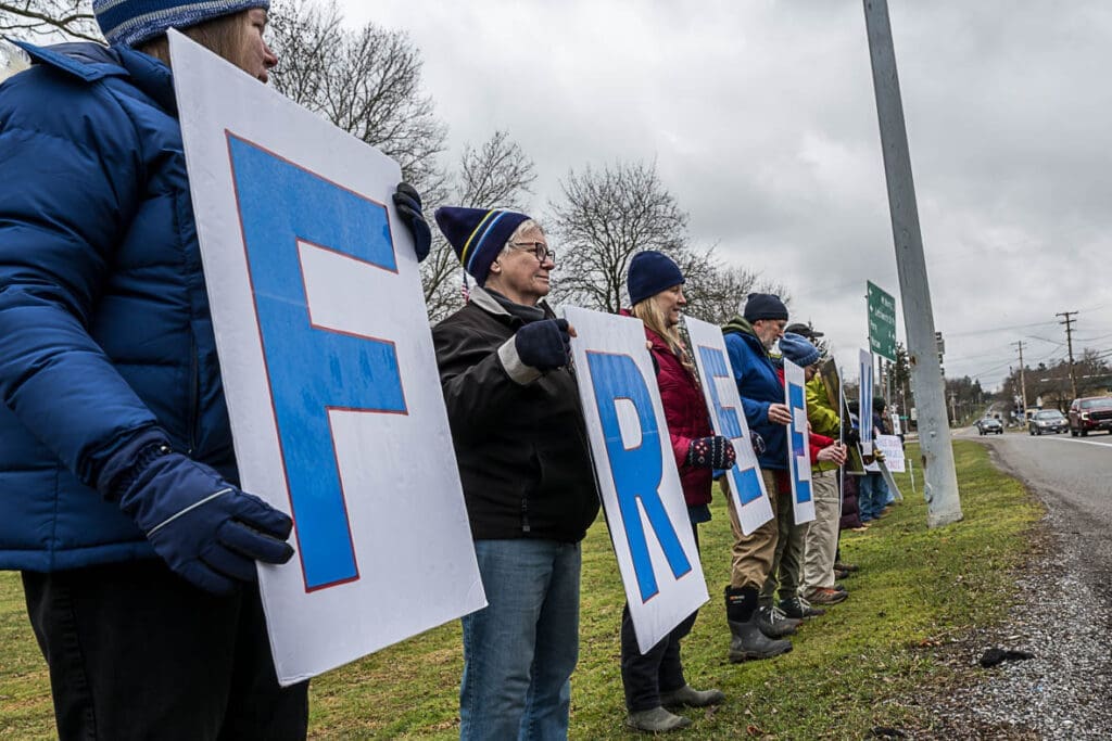 People holding large letters spelling FREE roadside