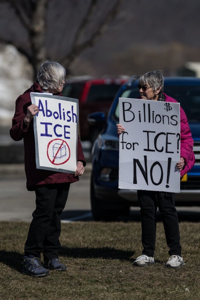 Two protesters holding signs opposing ICE funding and abolishment