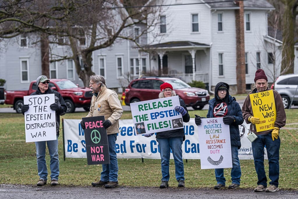 Protesters holding signs about Epstein files and war