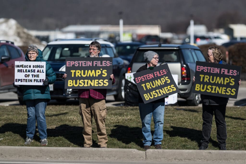 Protesters holding Epstein Files Trump signs at rally