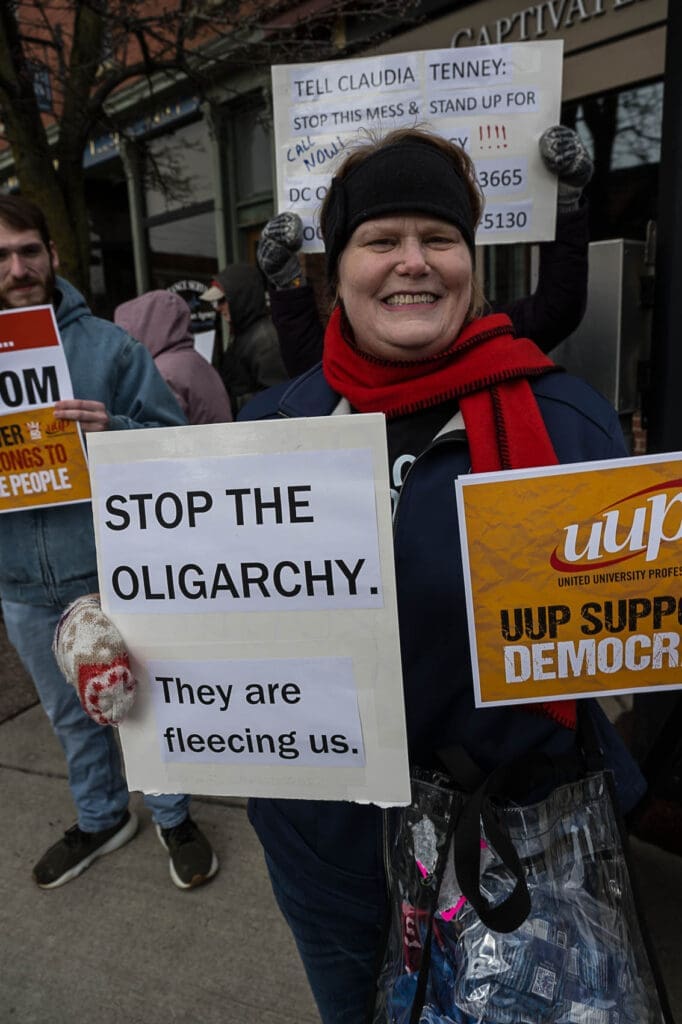 Protester holding 'Stop the Oligarchy' sign.