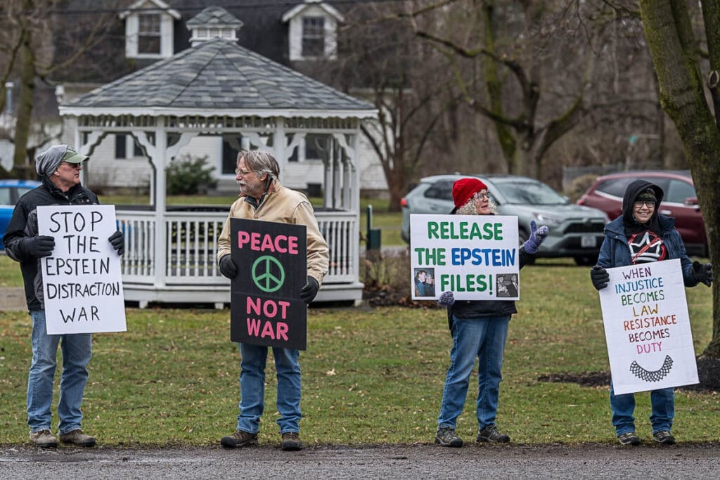 Protesters holding signs about Epstein files and peace