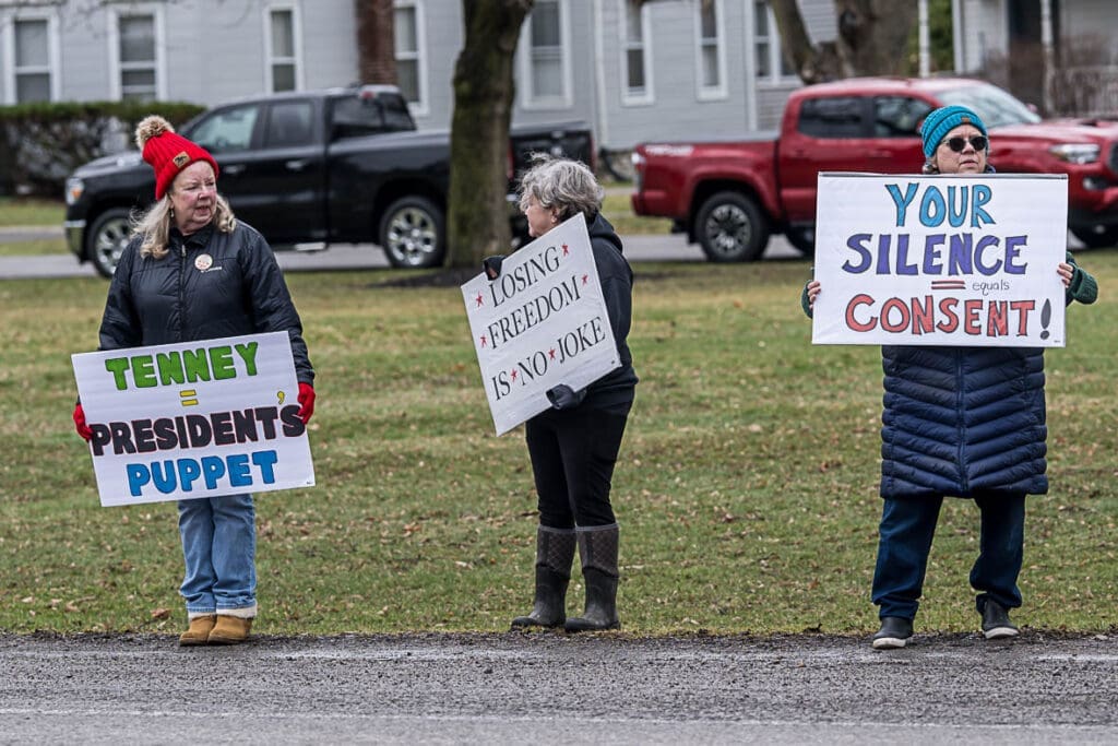 Three women holding political protest signs outdoors
