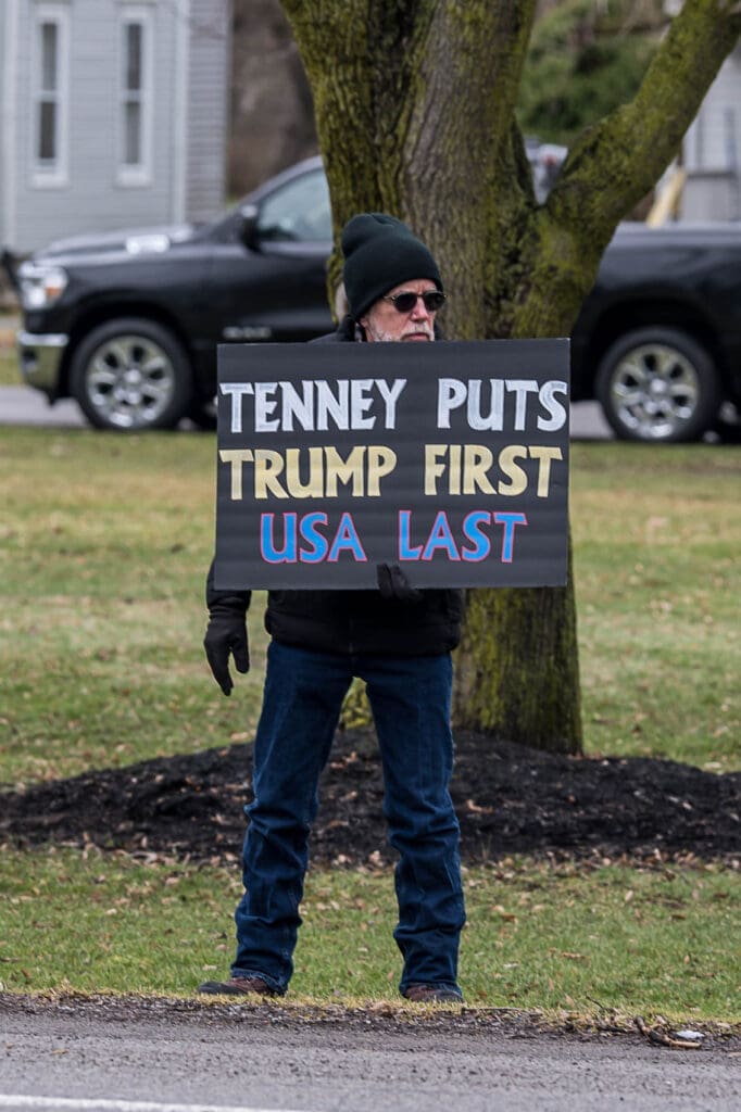 Man holding sign criticizing Tenney and Trump.