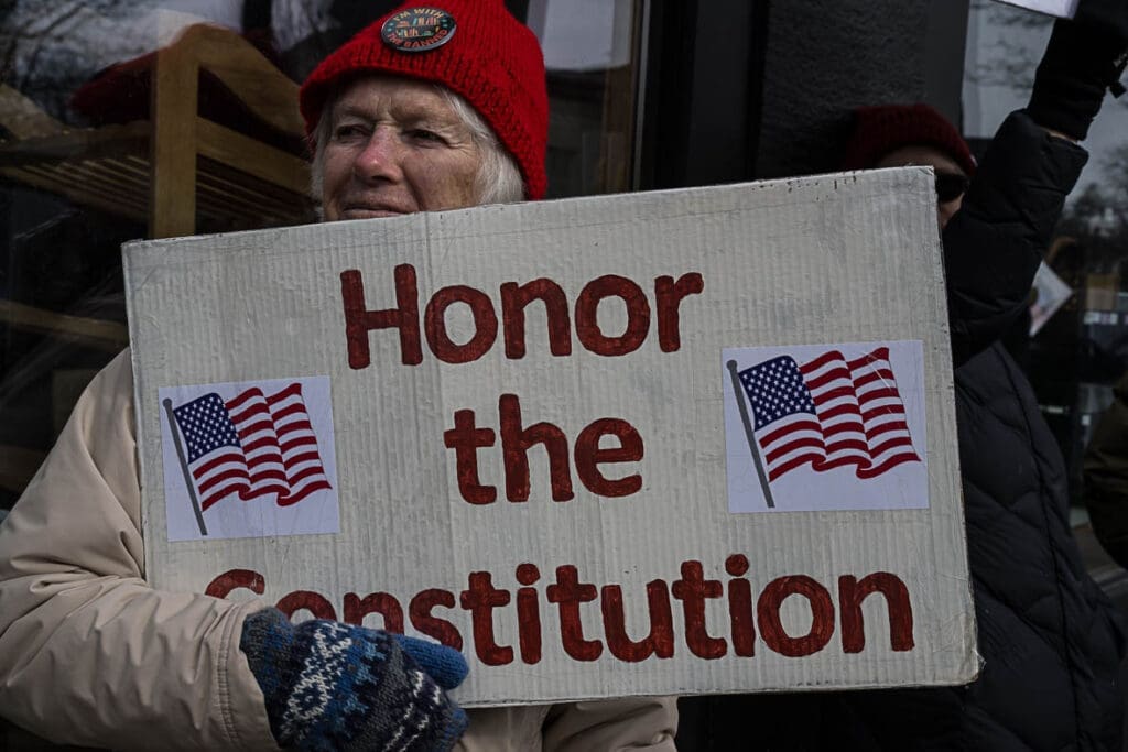 Protester holding Honor the Constitution sign with flags