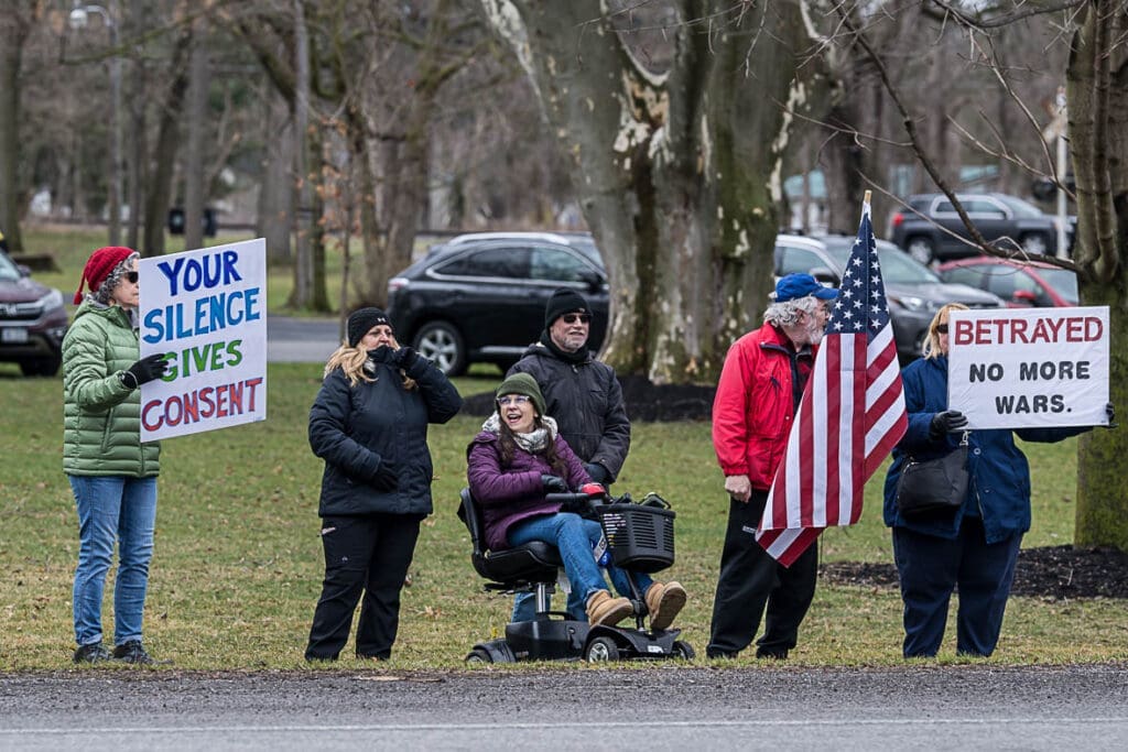 Protesters holding anti-war signs and American flag