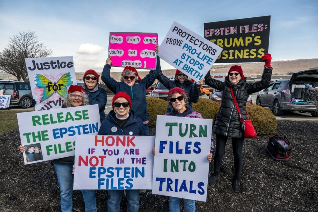 Protesters holding signs demanding release of Epstein files