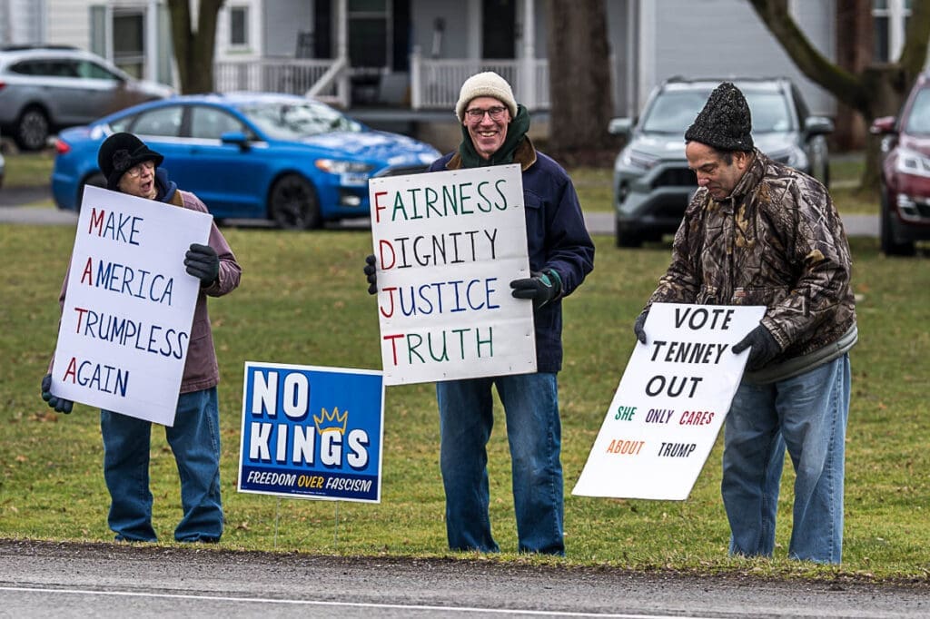 Protesters holding anti-Trump political signs outdoors
