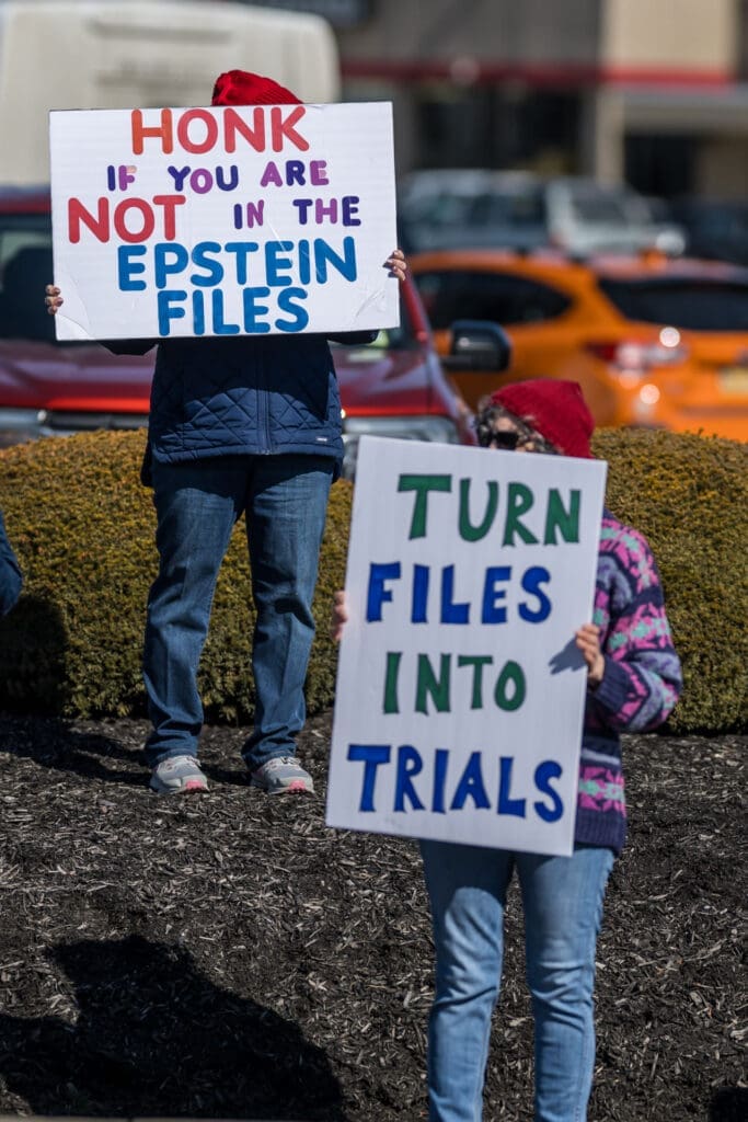 Protesters holding signs about Epstein files and trials