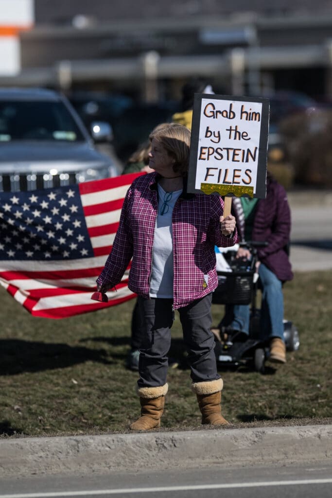 Protester holding Epstein Files sign with American flag