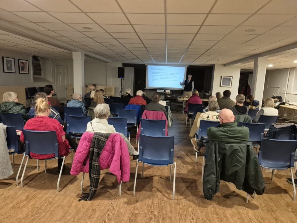 Community meeting with speaker presenting to seated audience