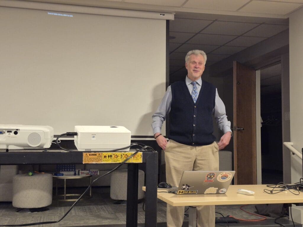Man giving presentation beside projector screen