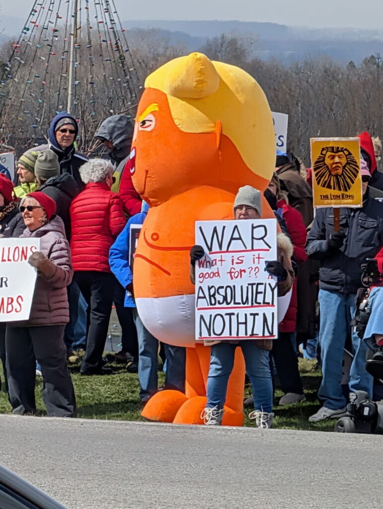 Protesters with orange caricature balloon and anti-war sign
