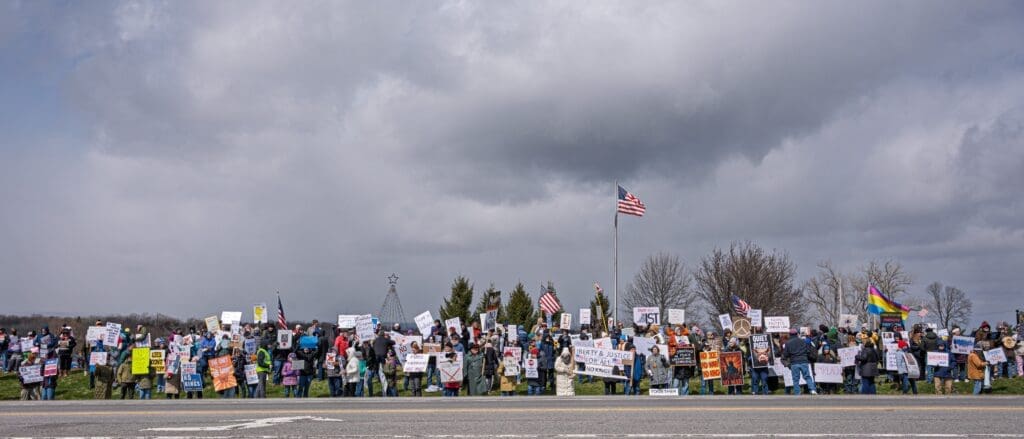 Large roadside protest with signs and American flag