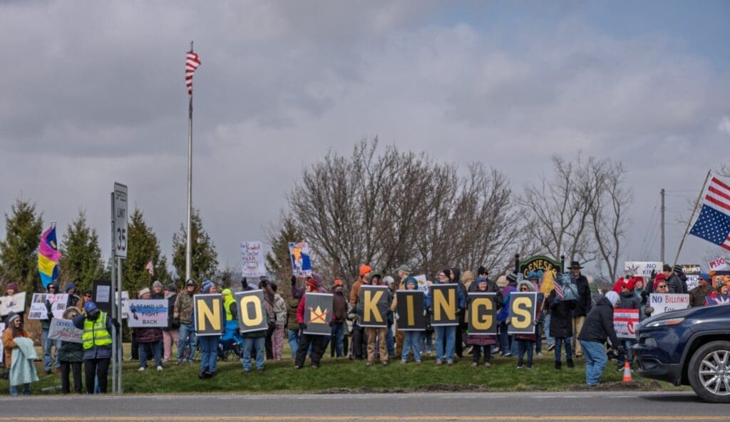 Protesters holding 'No Kings' signs roadside rally