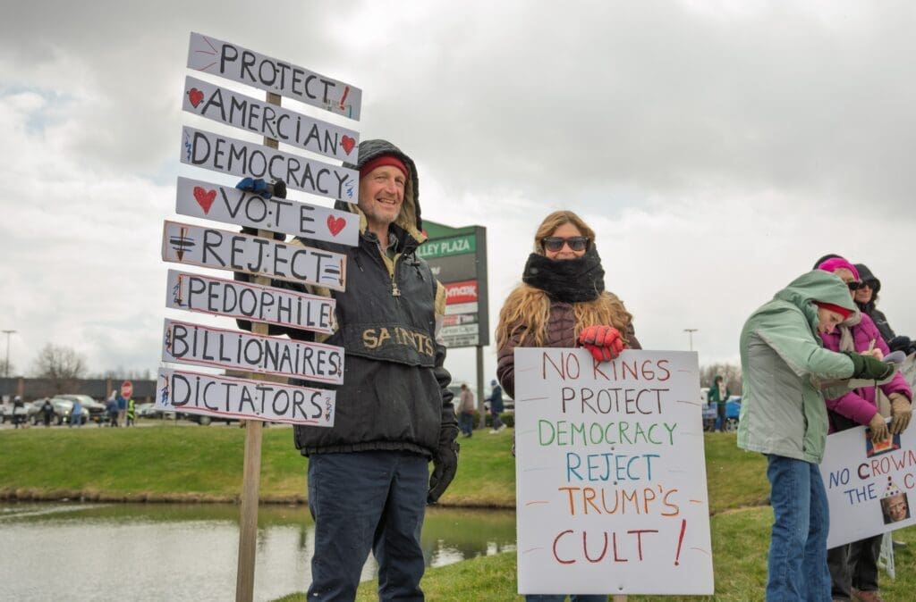 Protesters holding signs supporting democracy and rejecting Trump
