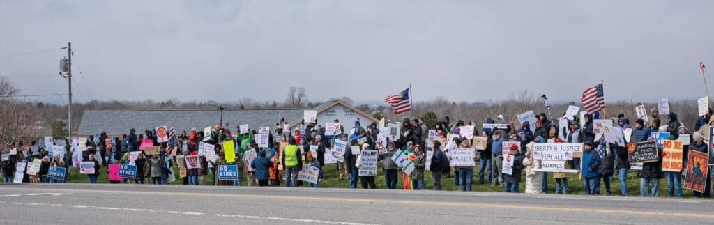 Large roadside protest with signs and American flags